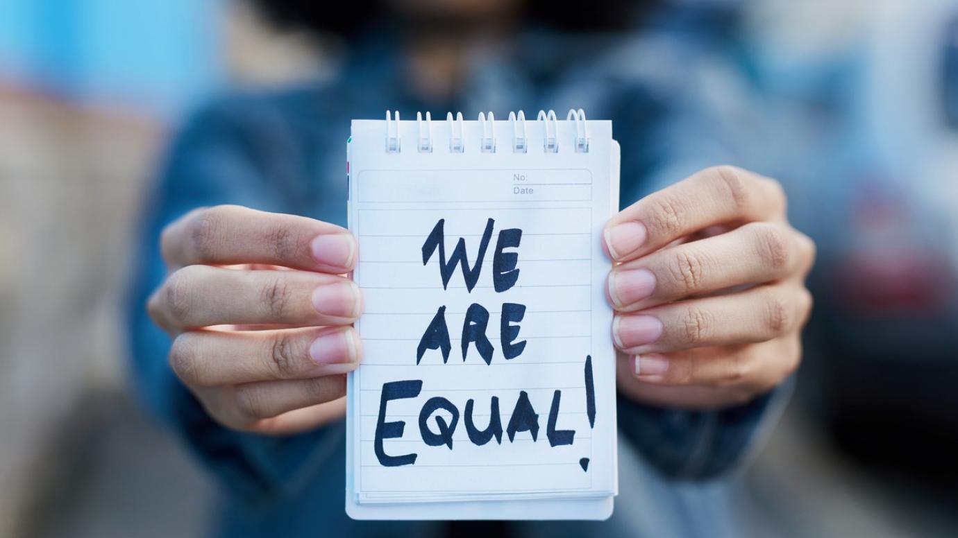 Kvinna som håller upp en skylt med texten: ”We are equal!” (Vi är jämlika!)
