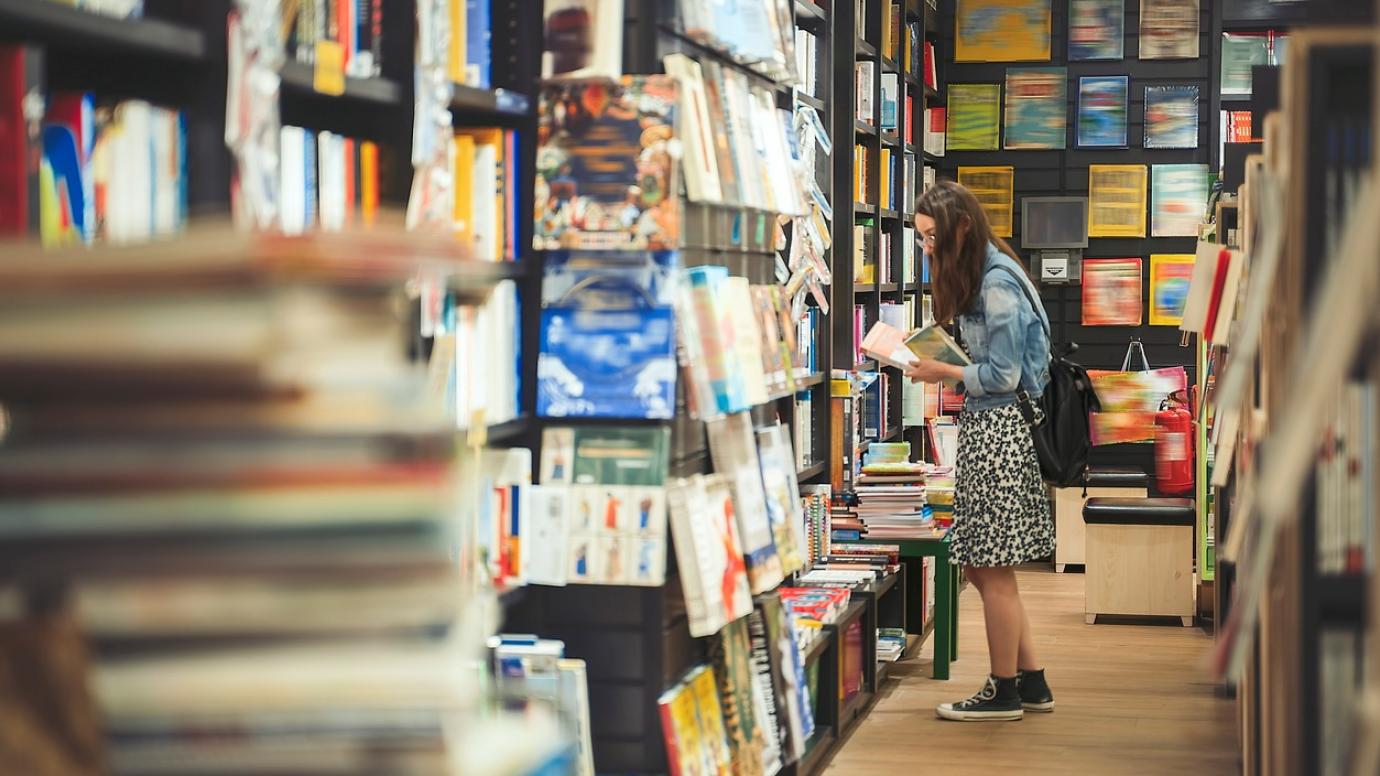 Dívka prohlížející si knihy v knihkupectví